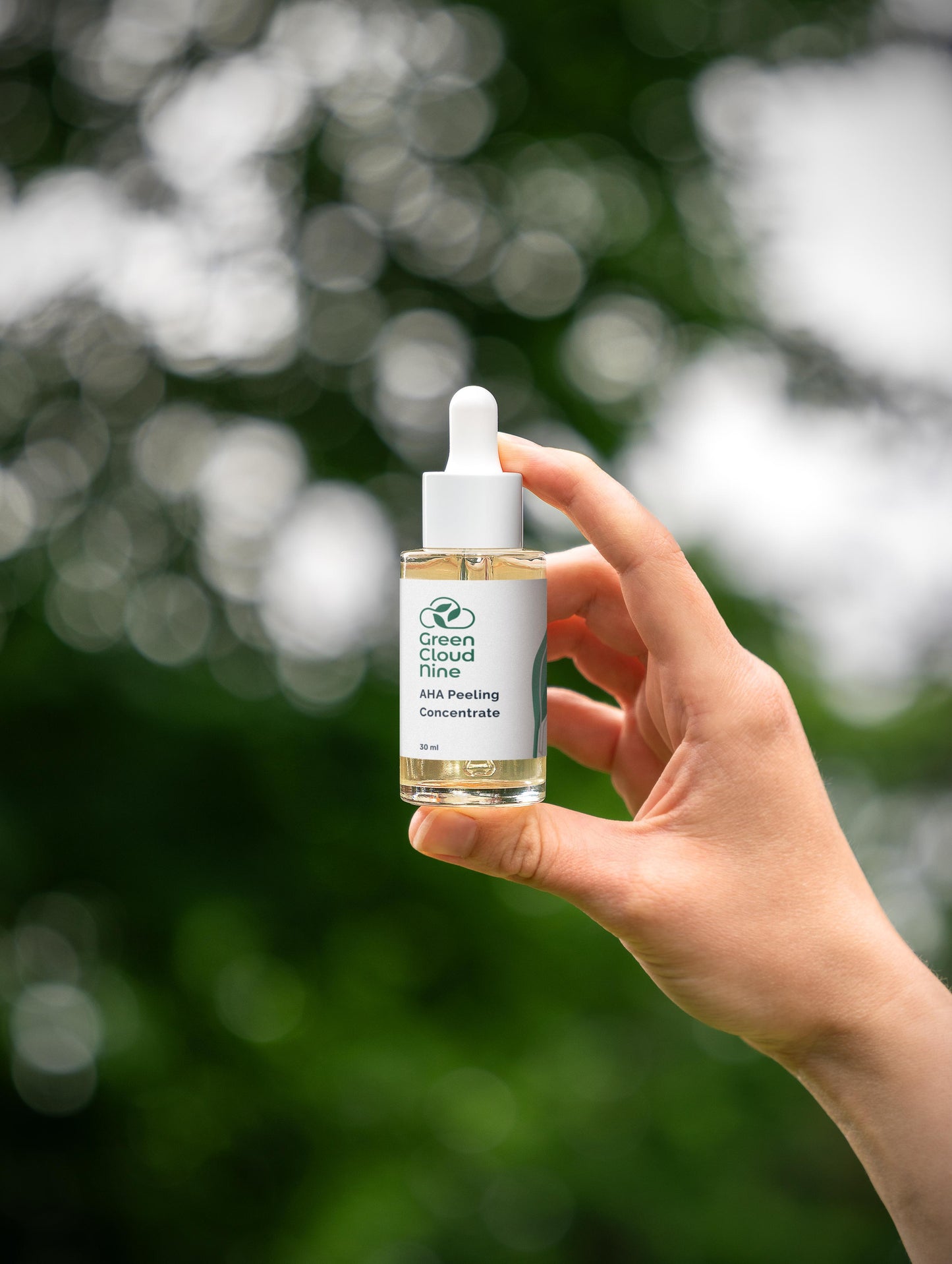 Hand holding a bottle of 'Green Cloud Time' product against a blurred natural background (front)