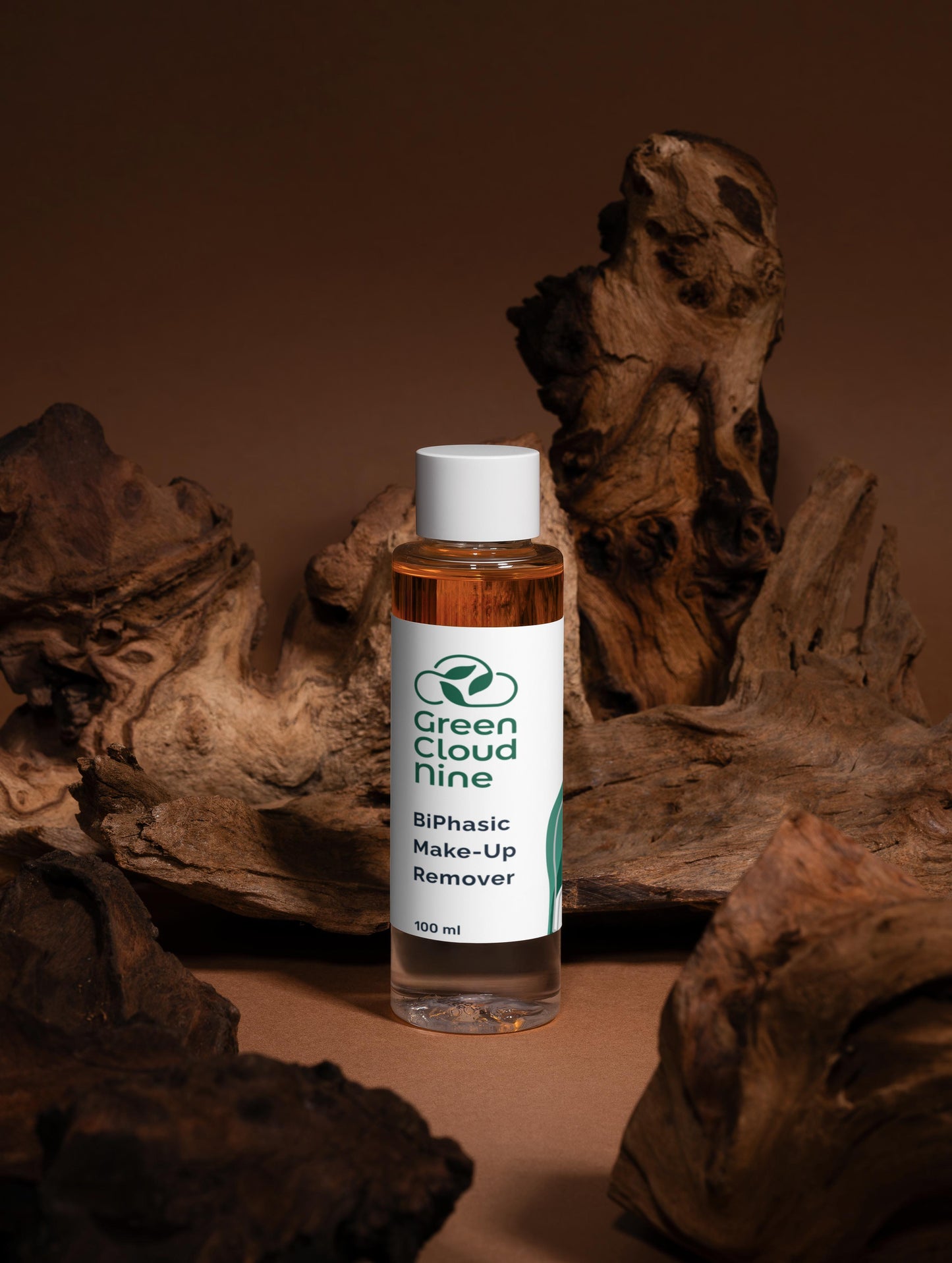 Bottle of Green Cloud Nine BiPhasic Make-Up Remover surrounded by natural wood elements on a brown background