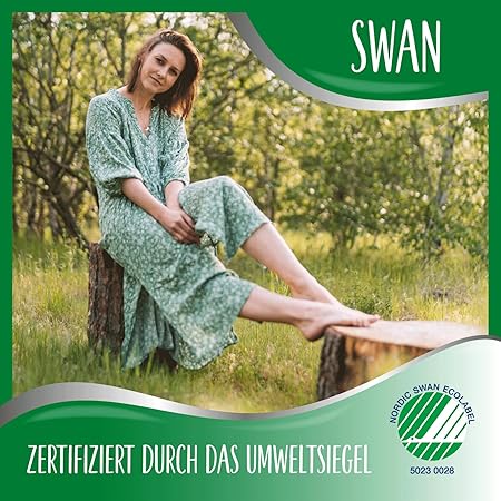 Woman in a green floral dress sitting on a log in a forest, with the Nordic Swan Ecolabel certification for eco-friendly products.