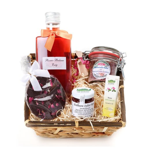 Gift basket with rose vinegar, rose salt, strawberry jam, rose oil, and rose chocolate on straw filling.