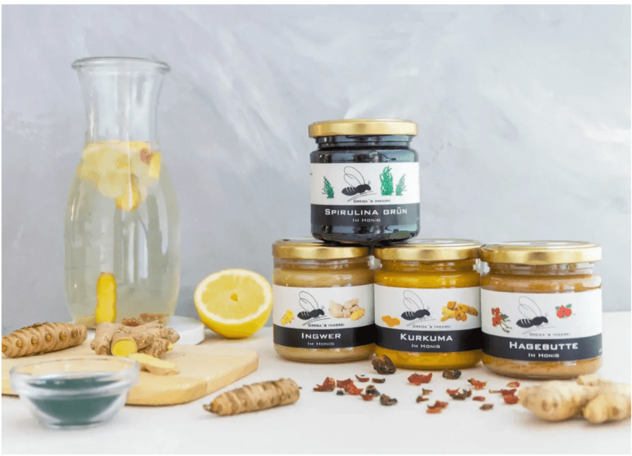 4 pack of Immune System Booster Honey.spirulina, ginger, turmeric, rosehip. Displayed with lemon and turmeric root.