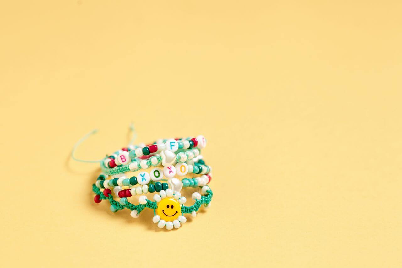 Bracelets from Jewellery DIY set "Lovely You #GirlPower", on a ochre background