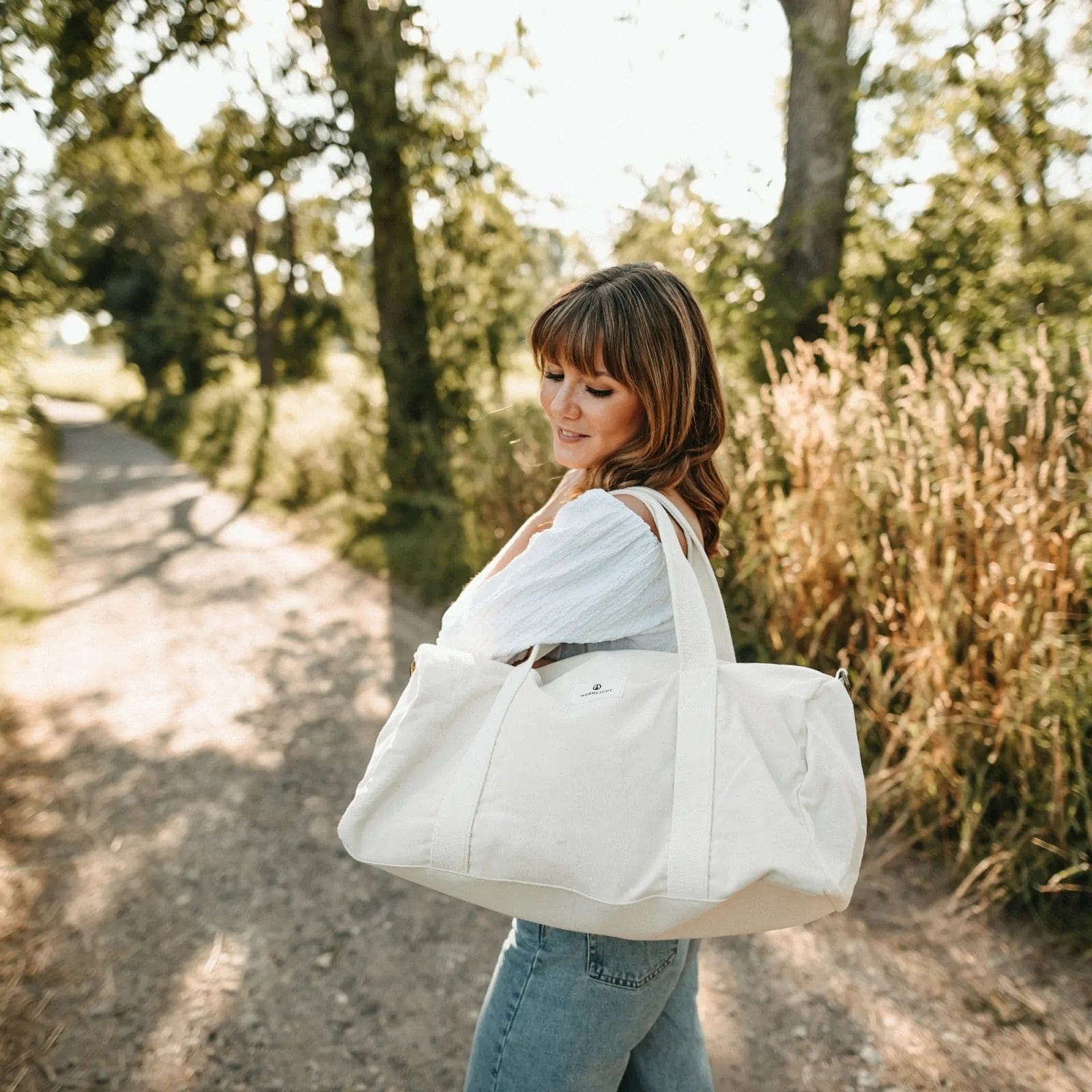 Nordlicht organic cotton travel bag worn by woman on a forest path, stylish and eco-conscious travel choice