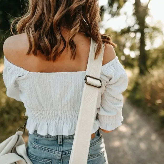 Close-up of woman carrying Nordlicht organic cotton travel bag with wide strap on a summer forest walk