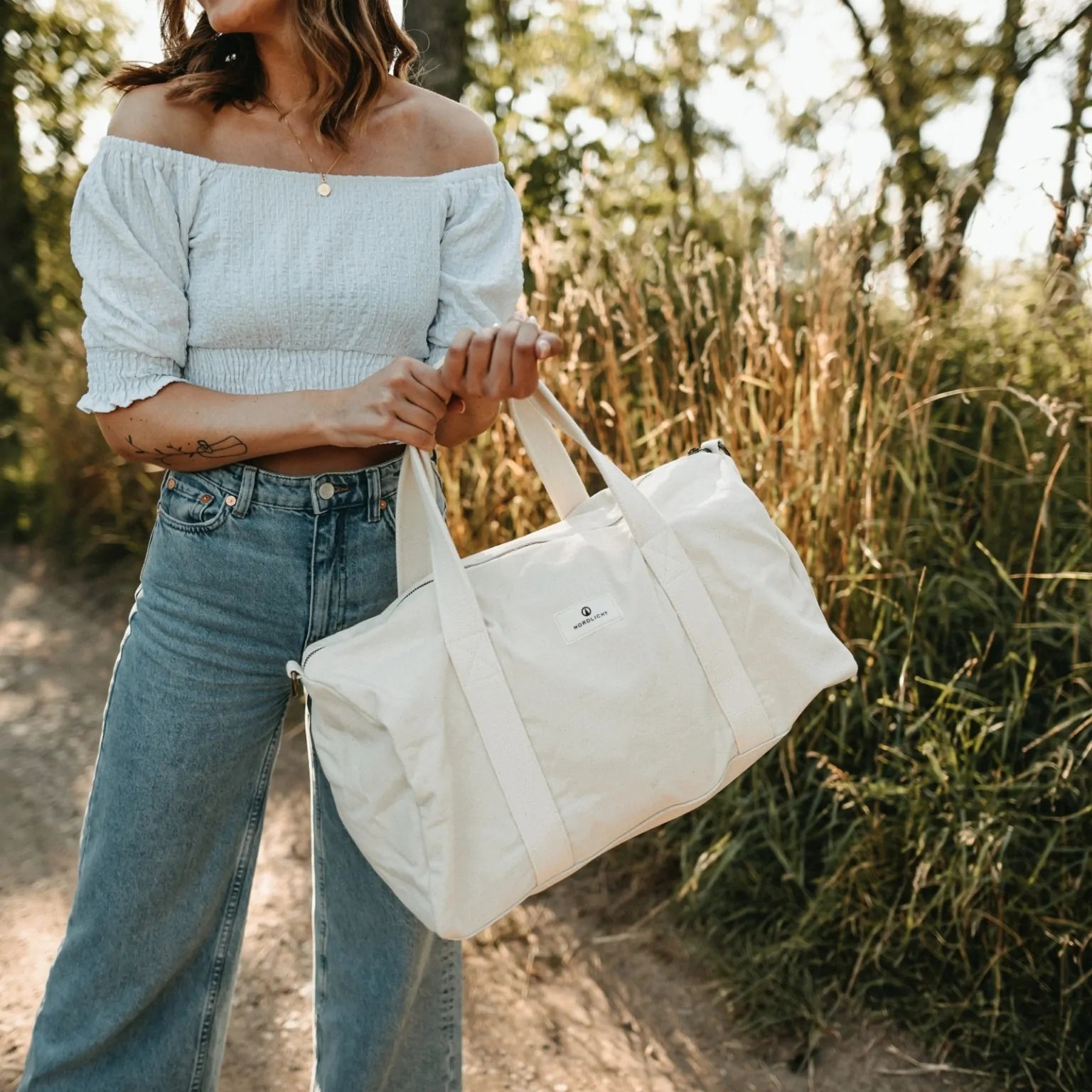 Nordlicht eco cotton weekender bag held by woman in nature, ideal for conscious travel and sustainable style