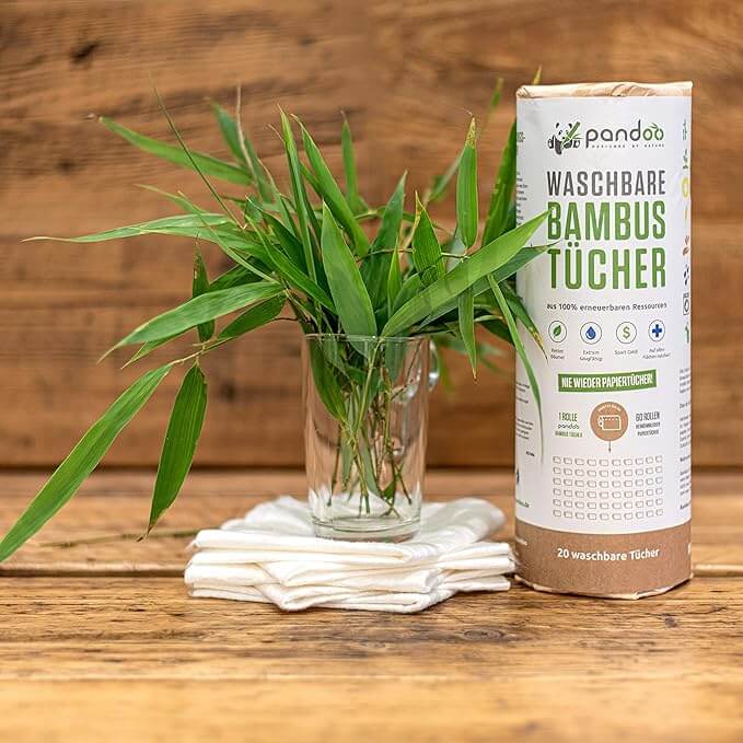 Pandoo bamboo kitchen roll displayed closte to a plant. over a wooden table