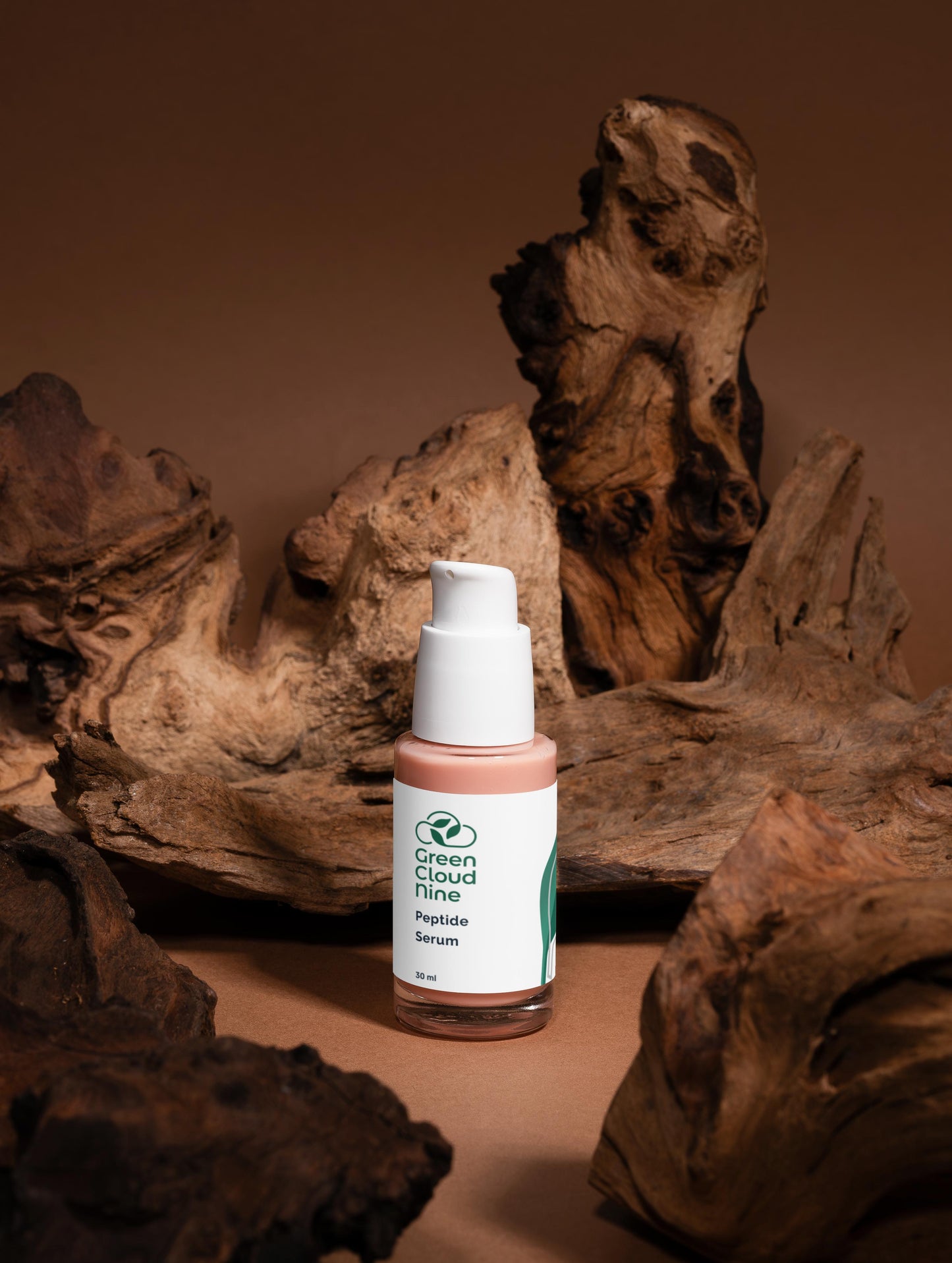 Bottle of Green Cloud Nine Peptide Serum on a brown background with natural wood elements.