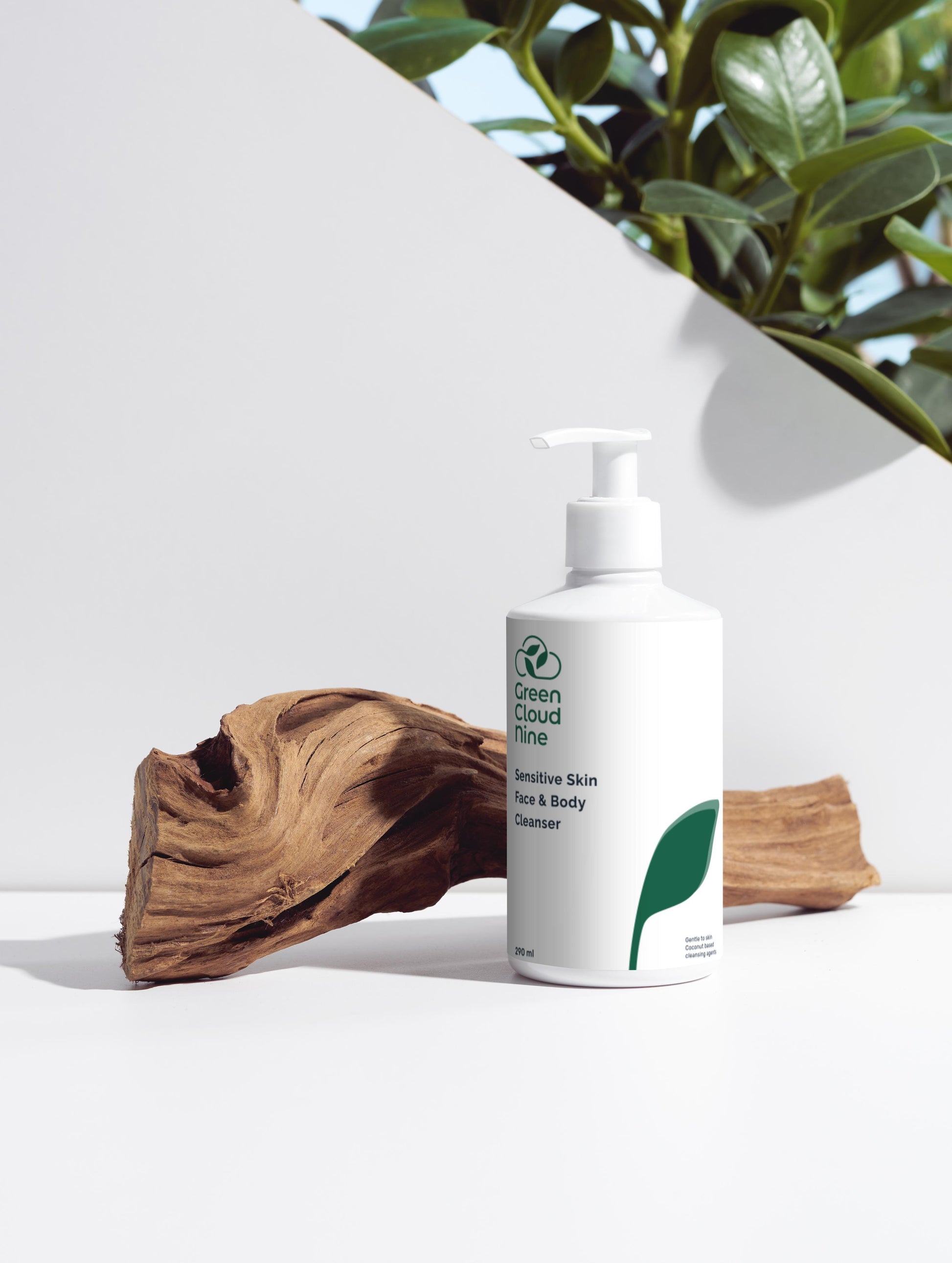 Sensitive Skin Face & Body Cleanser with Green Cloud Nine logo. White pump on a white background with plants and wood