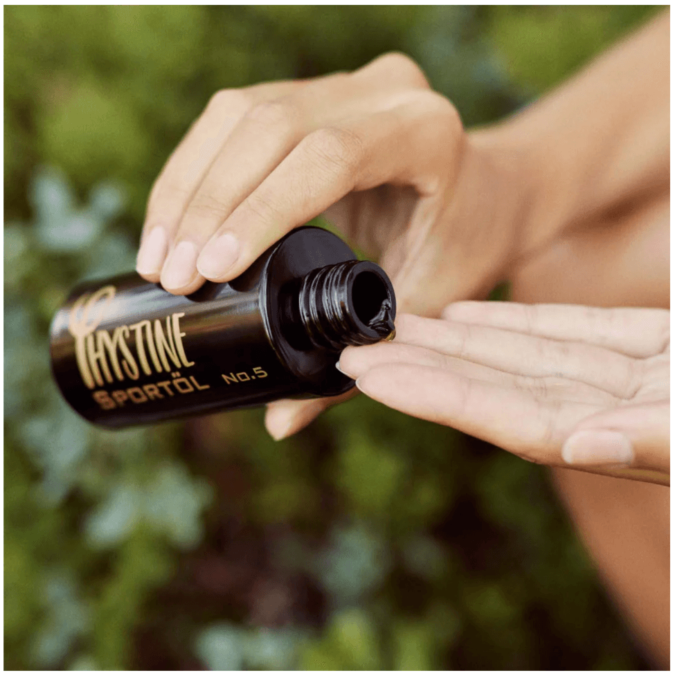 Hand pouring Phystine Sportöl No.5 onto fingers, organic vegan oil for muscle massage and skin care.