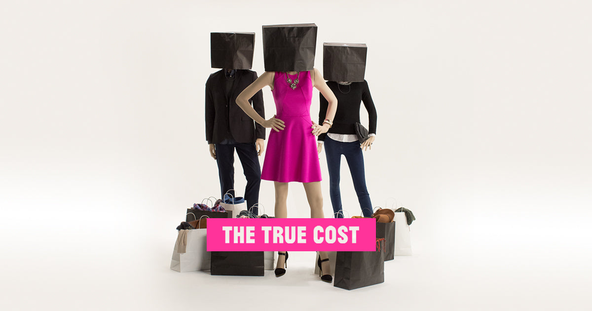 Three individuals with boxes on their heads and numerous bags scattered on the ground from The True Cost cover