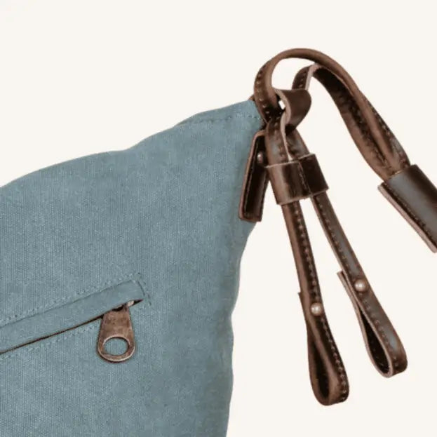 Close-up of Turquoise canvas and leather handbag with adjustable straps and a loop closure, eco-friendly and handmade.