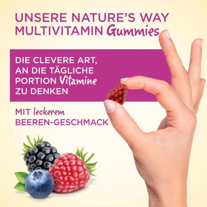 A hand holds a berry-shaped gummy above mixed berries, highlighting Nature's Way Multivitamin Gummies with berry flavor.