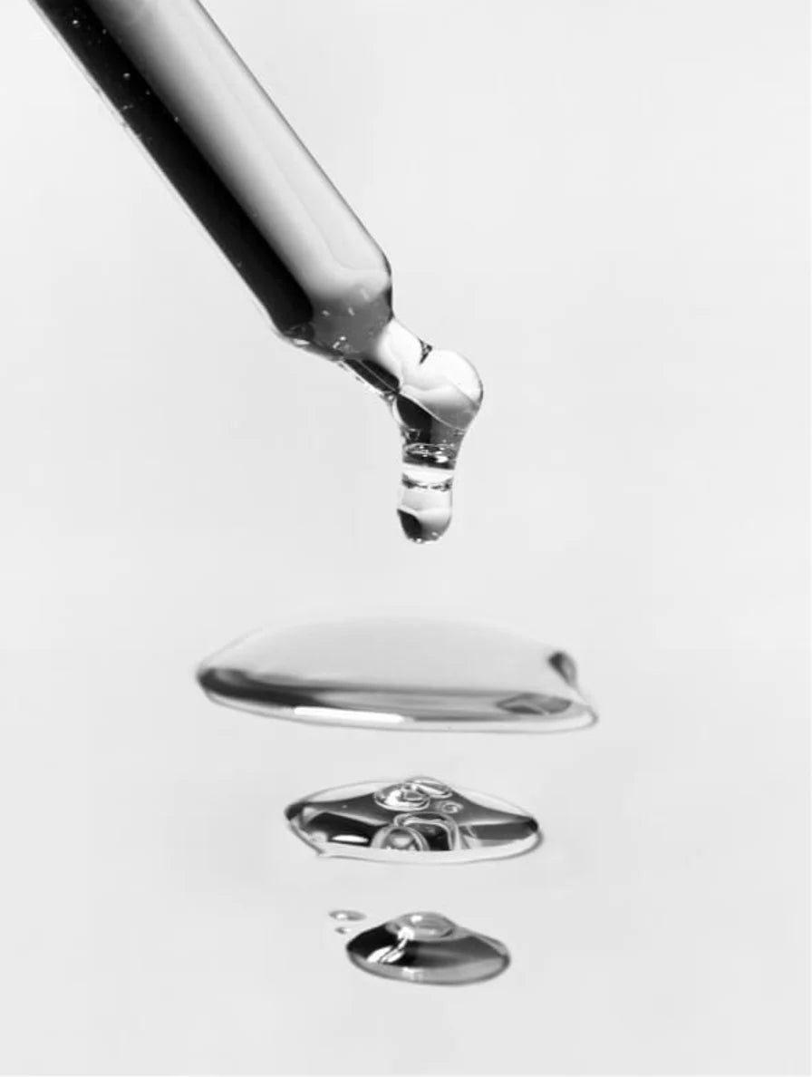 Close-up of a dropper with liquid dripping onto a white surface. For KIND Rituals