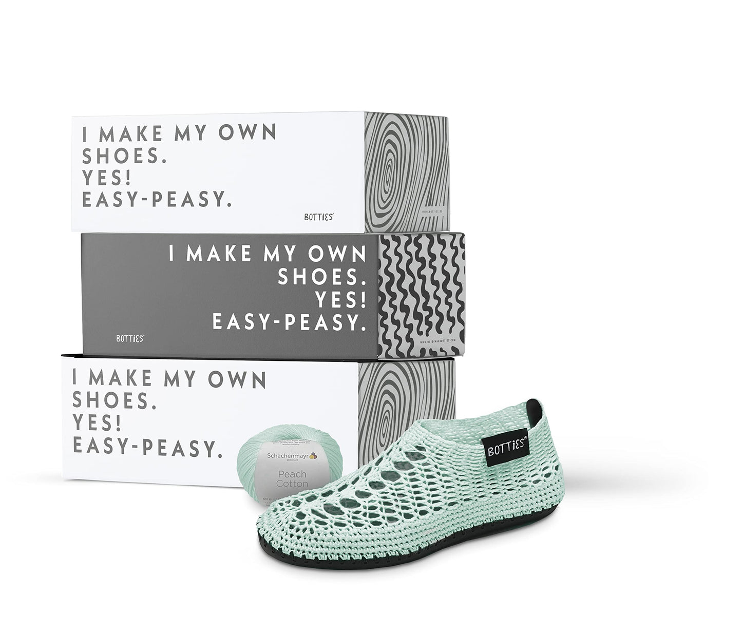 A crocheted peppermint shoe, spool of thread, and three boxes from BottiesXSchachenmayr