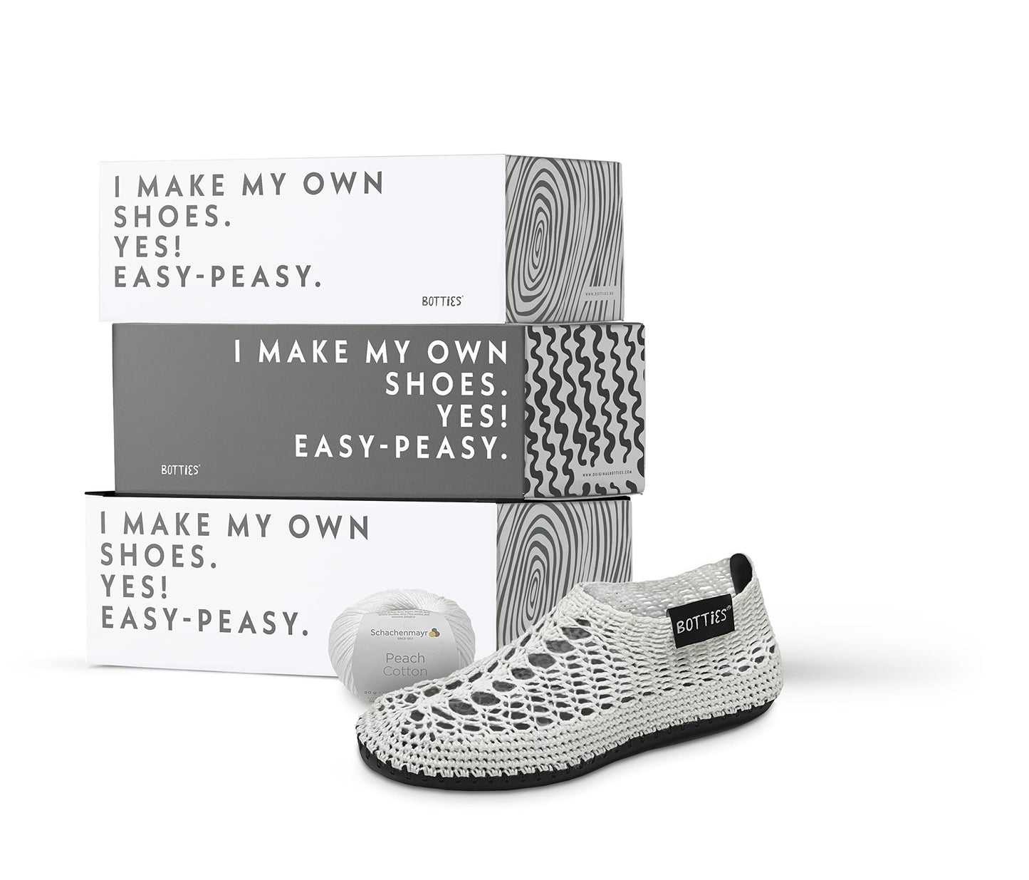 A crocheted white shoe, spool of thread, and three boxes from BottiesXSchachenmayr
