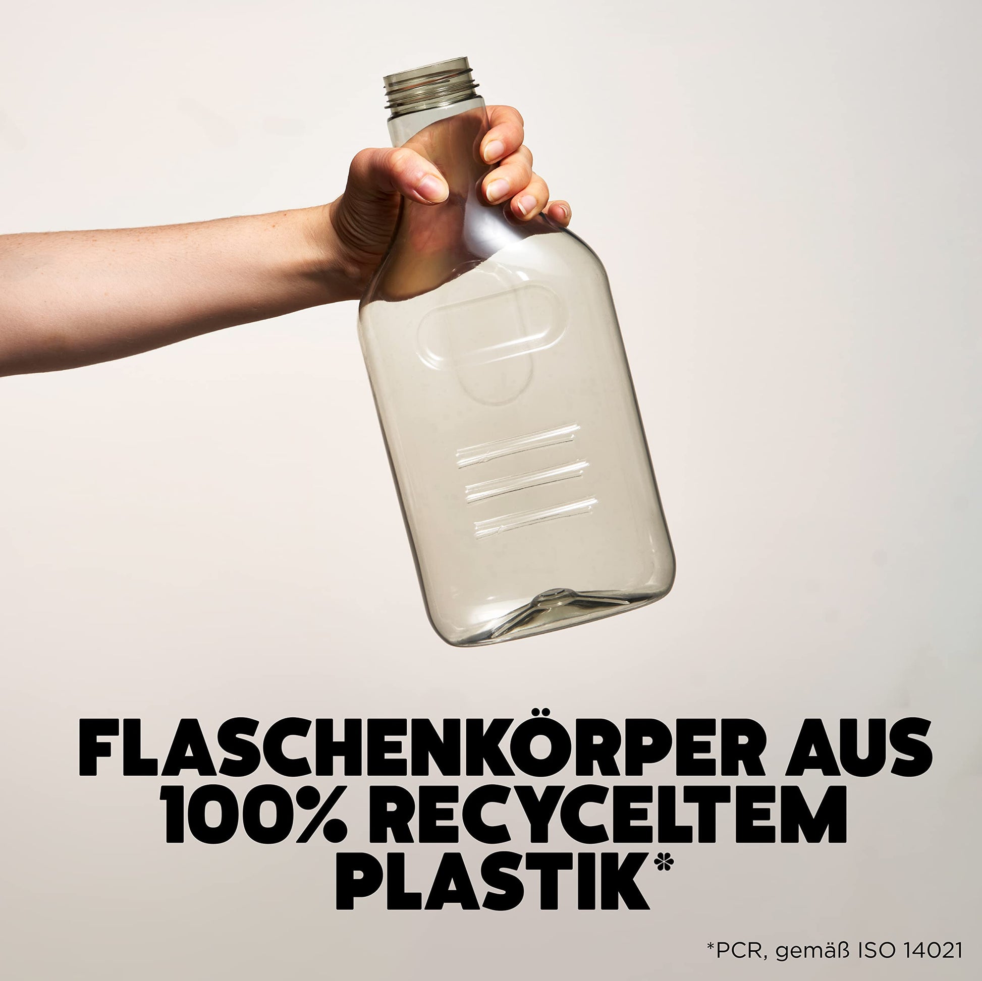 A hand holding an empty Ecover bottle made from 100% recycled plastic