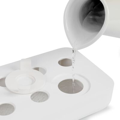 Water being poured from a white jug into the reservoir of a Livoo indoor garden hydroponic base