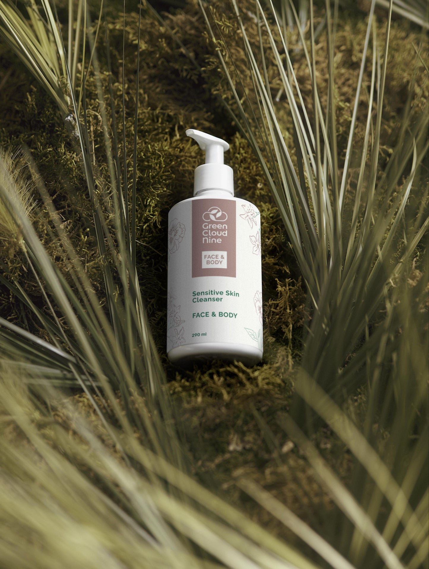Bottle of Green Clinical Face & Body Sensitive Skin Cleanser on a natural background with plants.