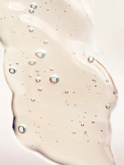 Close-up of a beige gel or cream with bubbles on a light pink background. For KIND Rituals